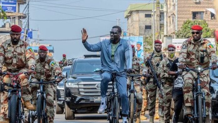 Le Président guinéen Mamadi Doumbouya salue la foule lors d'une promenade en vélo à Conakry